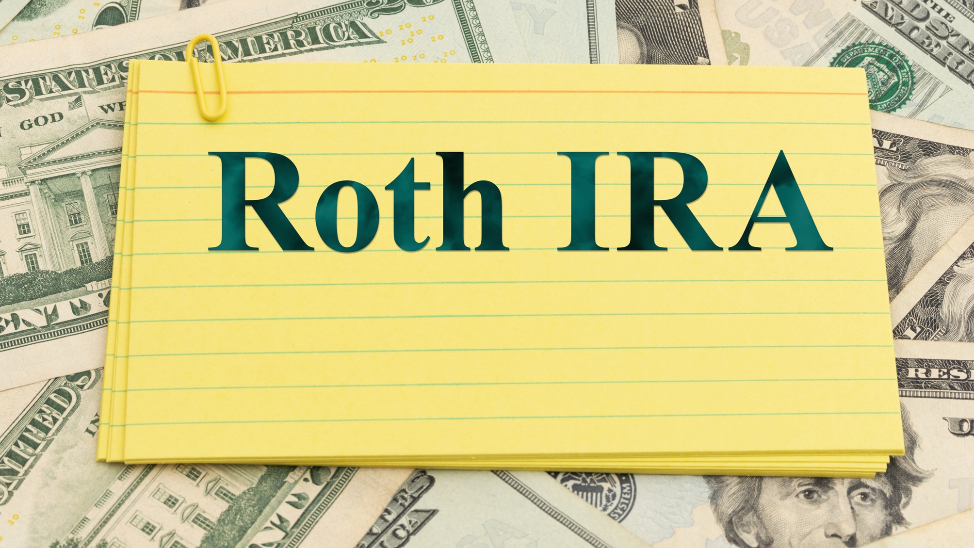 "Roth IRA" écrit sur une fiche jaune au-dessus de billets de 20 dollars.